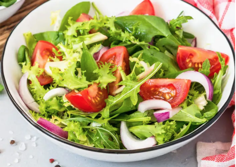 Ensalada de lechuga y espinacas con conejo al ajillo.